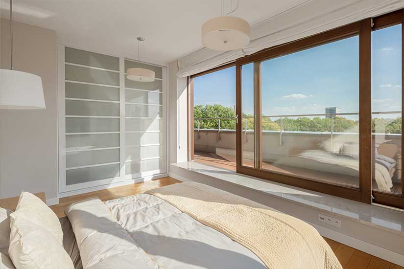 Chambre avec baie vitrée et porte-fenêtre en bois